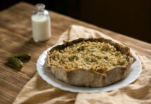 Warm rustic tart on a wooden table with a bottle of milk and pickles.