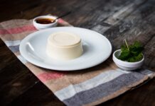 Delicious panna cotta served with fresh mint and sauce on a rustic table setting.