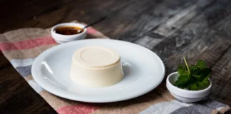 Bavaroise: Descubra o segredo da receita e surpreenda Delicious panna cotta served with fresh mint and sauce on a rustic table setting.