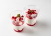 Two delicious red berry parfaits with cream, mint garnish in clear cups.