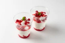 Semifreddo: Uma sobremesa irresistível Two delicious red berry parfaits with cream, mint garnish in clear cups.