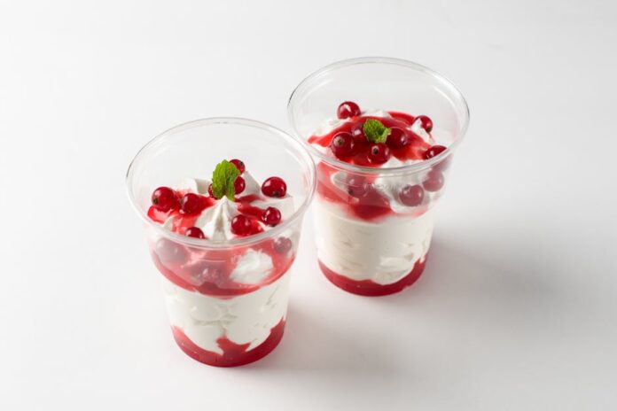 Descubra o Segredo do Semifreddo: Sobremesa Irresistível Two delicious red berry parfaits with cream, mint garnish in clear cups.