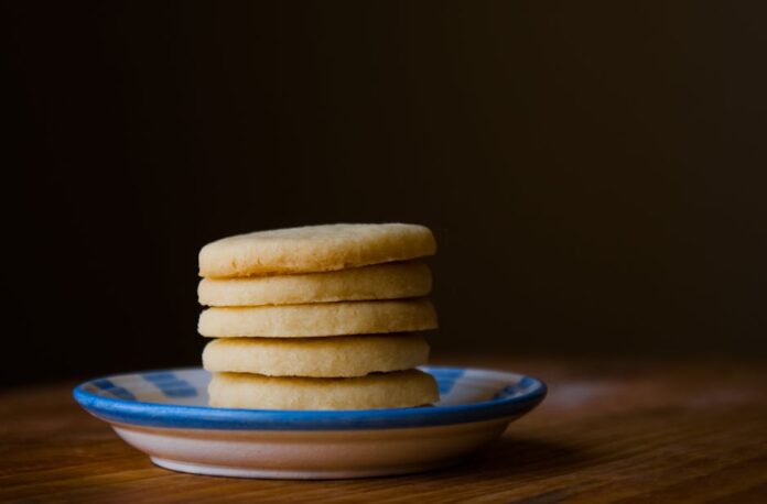 Descubra o Shortbread Perfeito: Segredos de um Sabor Único A stack of golden butter cookies on a ceramic plate, perfect for dessert inspiration.