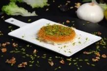 Kunafa: Uma delícia oriental Close-up of mouthwatering Arabic Kunafa topped with chopped pistachios.