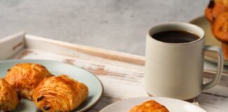 Enjoy a delightful breakfast with fresh croissants and a cup of coffee served on a rustic tray.