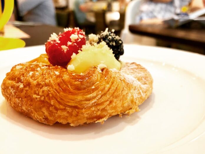 Descubra os Segredos do Kouign-amann: Delícia Francesa Irresistível Tempting pastry topped with berries and cream, perfect for dessert lovers.