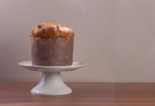 Panettone: Descubra os segredos do verdadeiro sabor High-quality image of a traditional Italian panettone on a white cake stand.