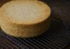 Freshly baked sponge cake resting on a wire cooling rack, perfect for desserts.