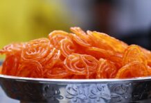 Close-up photo of crispy, orange Indian jalebi served in a decorative stainless steel bowl.