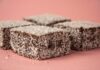 Close-up of scrumptious lamington cakes with desiccated coconut on a pink background.