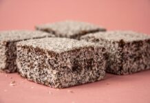 Lamington: Descubra o segredo do doce australiano Close-up of scrumptious lamington cakes with desiccated coconut on a pink background.