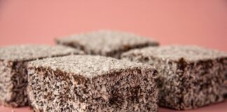 Close-up of scrumptious lamington cakes with desiccated coconut on a pink background.