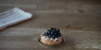 Tasty blueberry tart with powdered sugar on a wooden table in Berlin cafe. Perfect dessert for sweet tooth lovers.