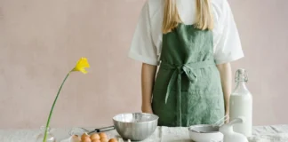 Pastiera: Descubra o segredo do doce italiano autêntico A person in a green apron preparing for Easter baking with eggs and milk indoors.