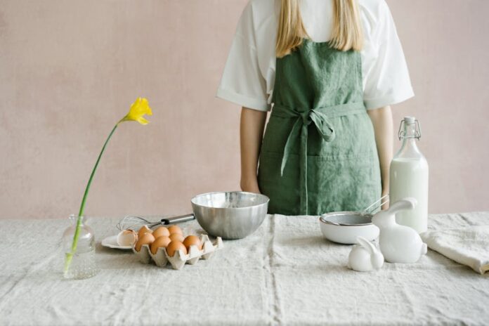 Pastiera: Descubra o Segredo do Doce Italiano Autêntico A person in a green apron preparing for Easter baking with eggs and milk indoors.