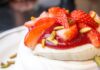 Close-up of a pavlova topped with fresh strawberries and pistachios, perfect for gourmet breakfast ideas.