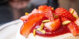 Close-up of a pavlova topped with fresh strawberries and pistachios, perfect for gourmet breakfast ideas.