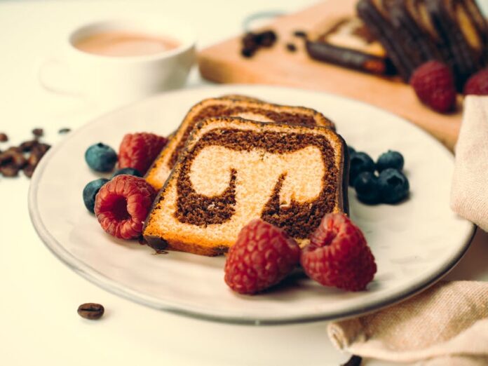 Pound Cake: Descubra o Segredo do Bolo Perfeito! Close-up of a marble cake with raspberries and blueberries, perfect dessert setting.
