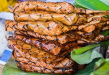 Stack of grilled suman wrapped in woven palm leaves, a Filipino delicacy.