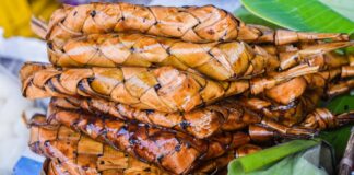 Stack of grilled suman wrapped in woven palm leaves, a Filipino delicacy.
