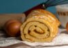 Close-up of a freshly baked roll cake with baking ingredients.