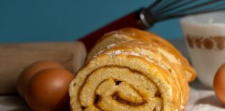 Close-up of a freshly baked roll cake with baking ingredients.