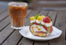 Receita de bolo simples: Segredo para o café perfeito Delicious fruit-filled Swiss roll with iced coffee on a wooden table.