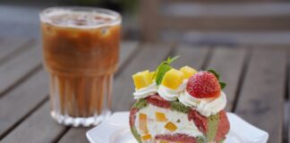 Delicious fruit-filled Swiss roll with iced coffee on a wooden table.
