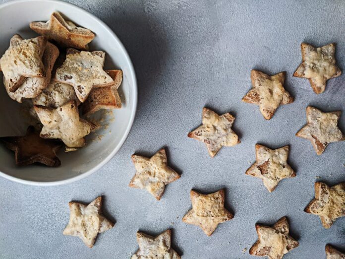 Receita de doce simples: descubra o segredo do sabor único! Flat lay of star-shaped homemade cookies in a bowl, perfect for Christmas treats.