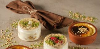 A rustic display of homemade desserts in glass and clay containers garnished with nuts and herbs.