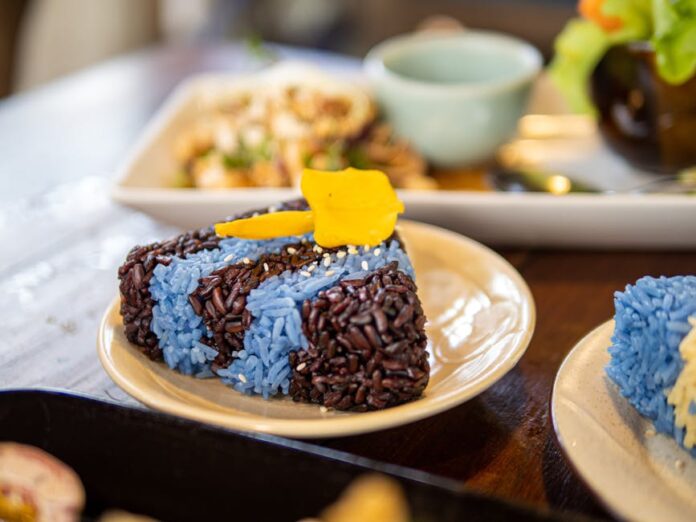 Receita de Rice Pudding: Segredos para um Doce Irresistível Close-up of vibrant blue and black sticky rice with mango on a plate, showcasing traditional Thai cuisine.