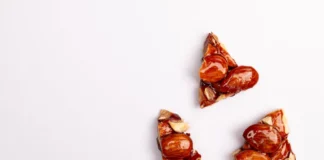 Toffee: Descubra os segredos do doce perfeito Close-up of almond brittle pieces on a white backdrop, offering tempting texture.