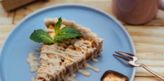 A mouthwatering slice of apple tart with caramel drizzle on a blue plate, garnished with mint leaves.